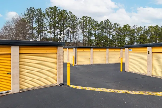 Drive-up storage units with yellow roll-up doors and easy vehicle access around corner layout