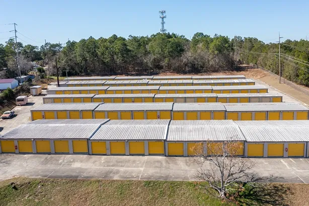 Drive-up storage units with yellow roll-up doors and wide concrete access lanes
