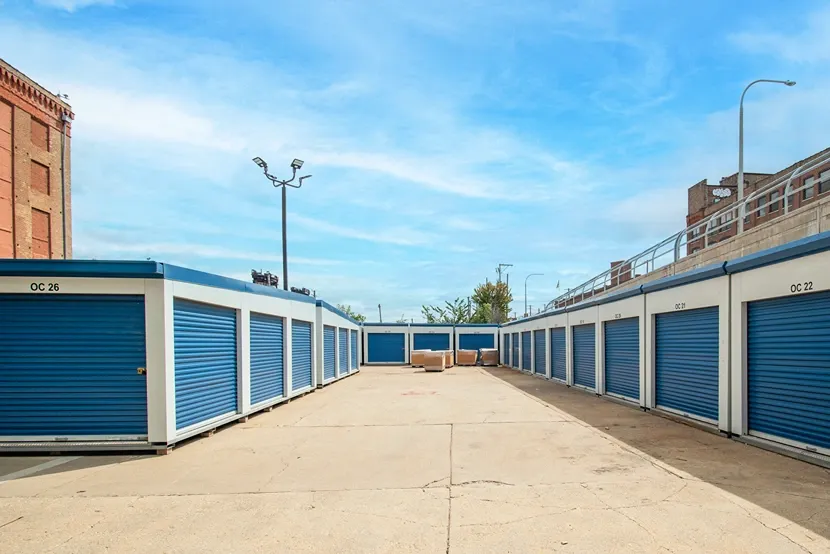 Row of drive-up storage units with blue roll-up doors and wide access lane at Devon Self Storage